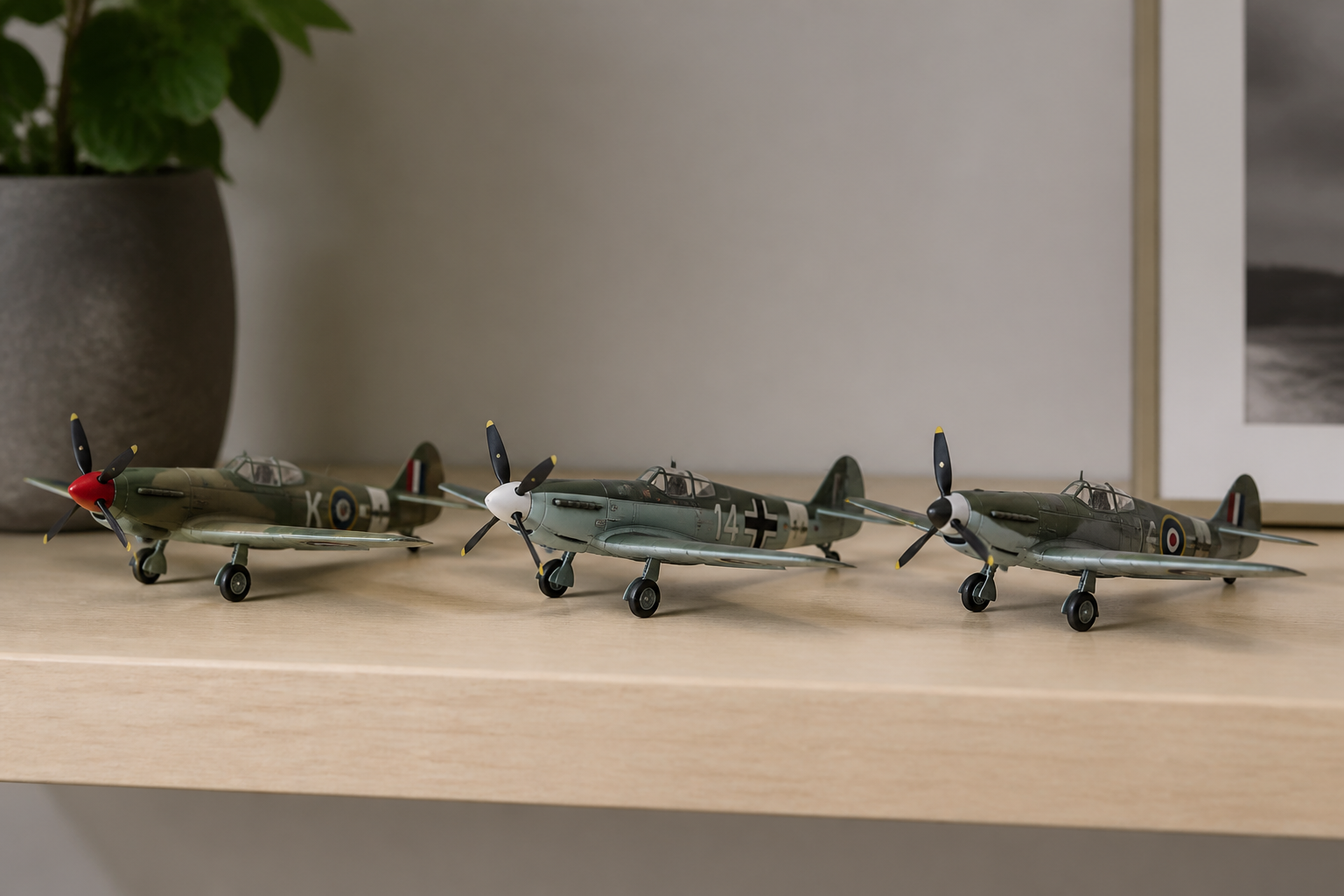 Three finished 1/72 propeller fighter models in wartime camouflage lined up on a pale wooden shelf, seen at eye level