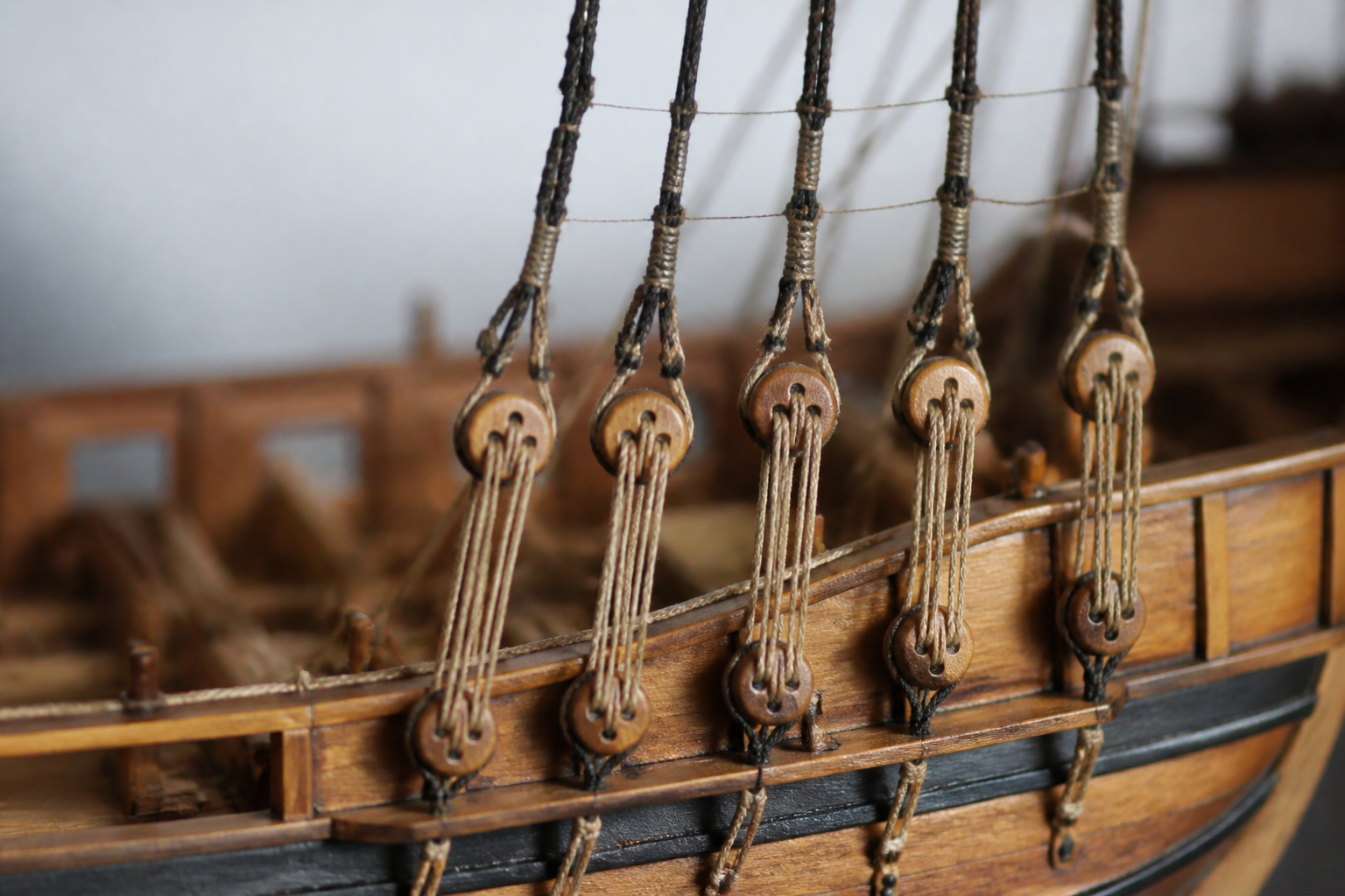 Close view of the standing rigging on a wooden ship model, showing deadeyes and lanyards between the shrouds and the channel